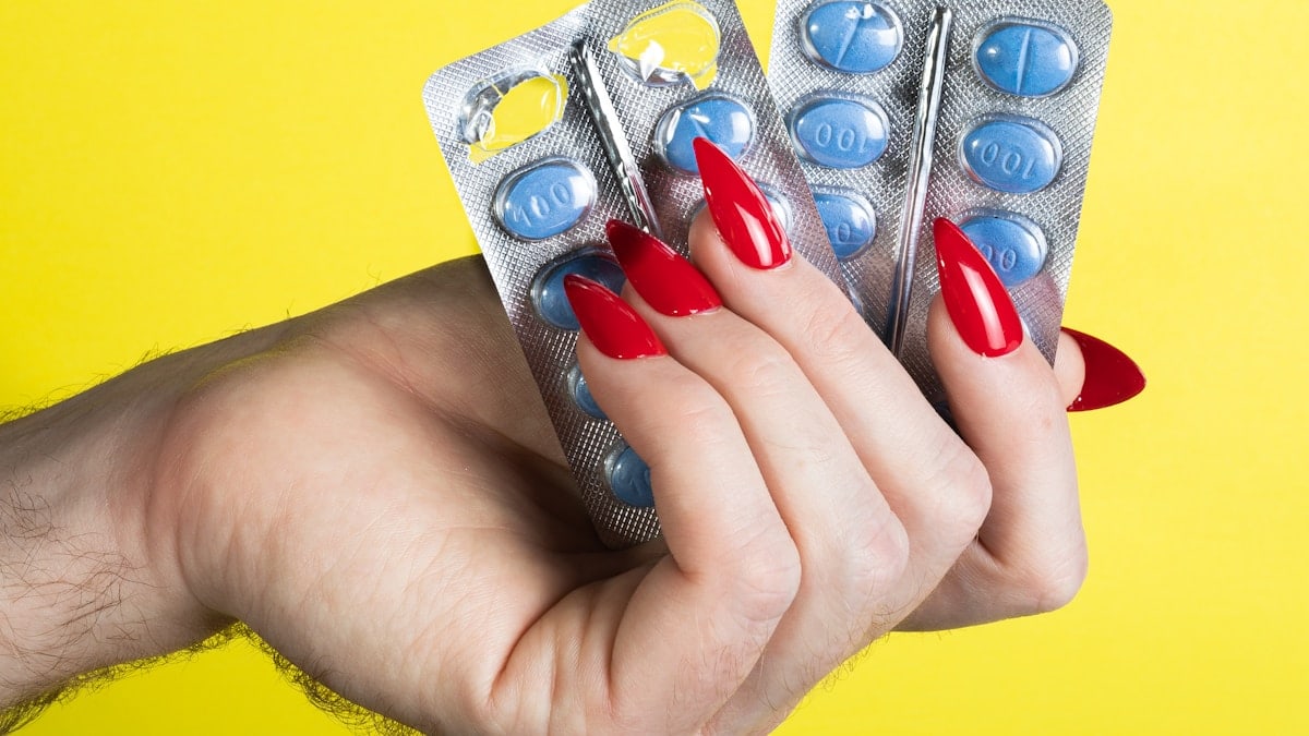a woman's hand holding two contraptions in front of a yellow background