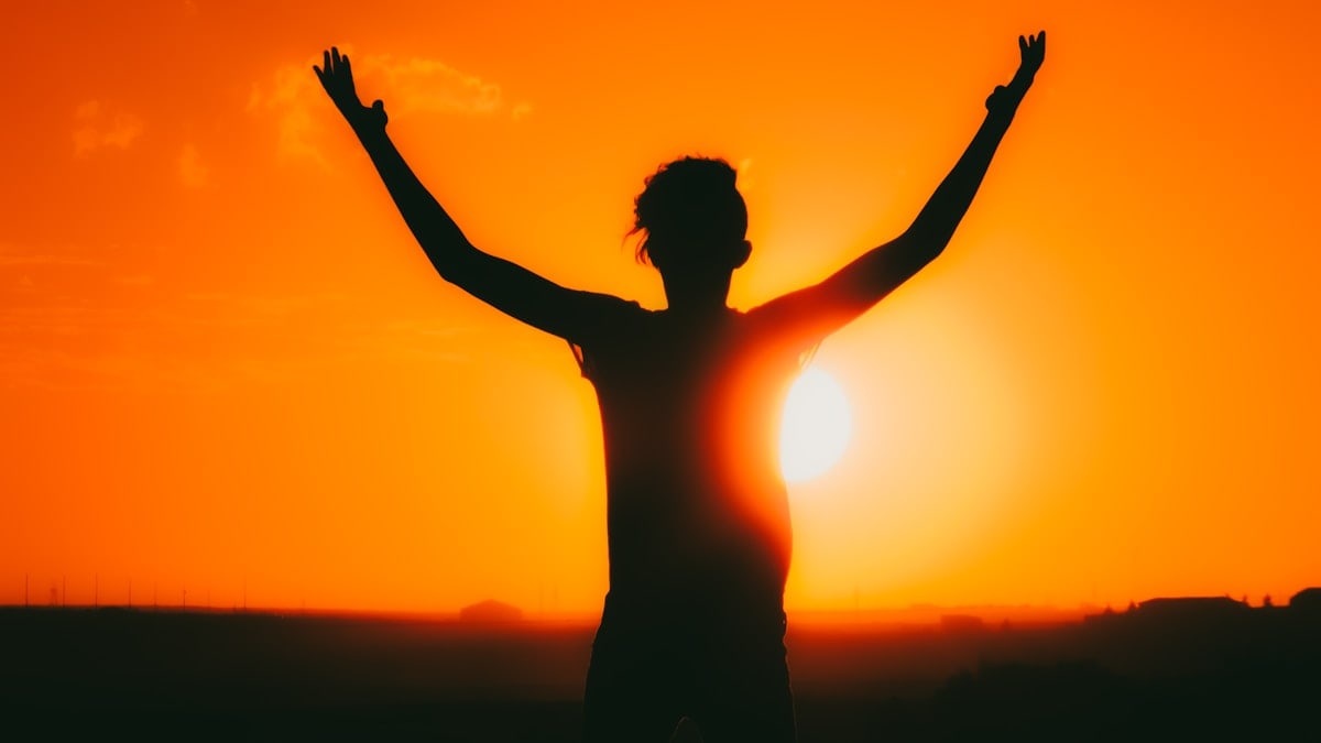 man open arms under the sunrise at sea